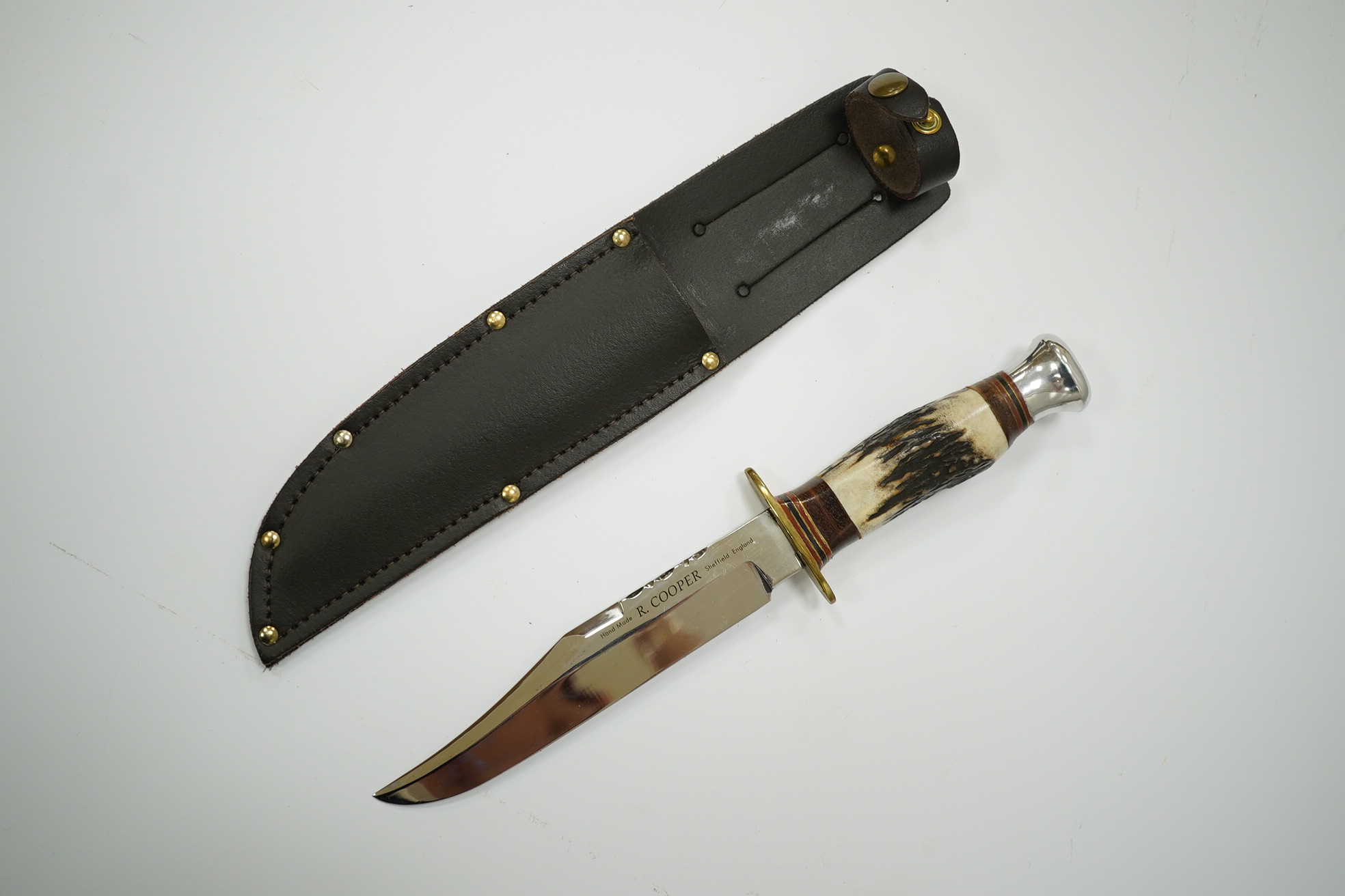 A small bowie knife by R. Cooper in its leather sheath, blade 15cm. Condition - good